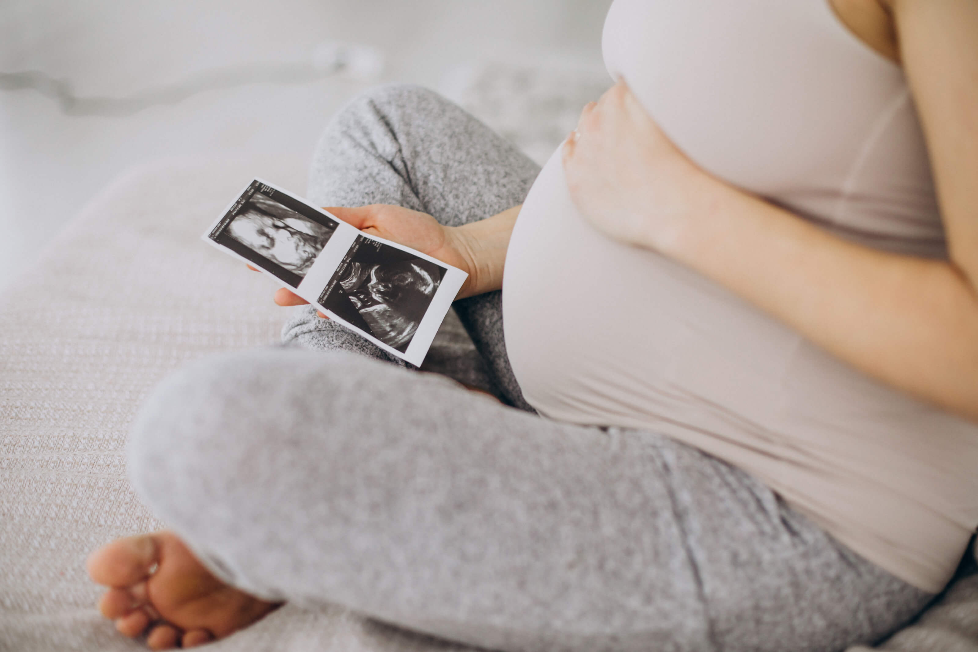 pregnant-woman-with-ultrasound-photo-sitting-bed (1)